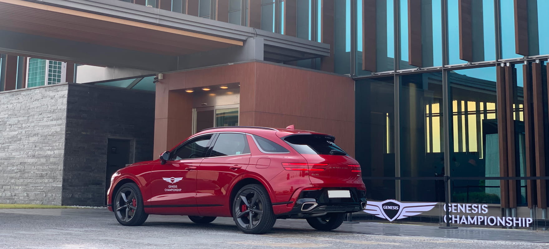 Rear side view of the official red Genesis GV70 SUV featuring the Genesis Championship logo and sleek tournament branding.