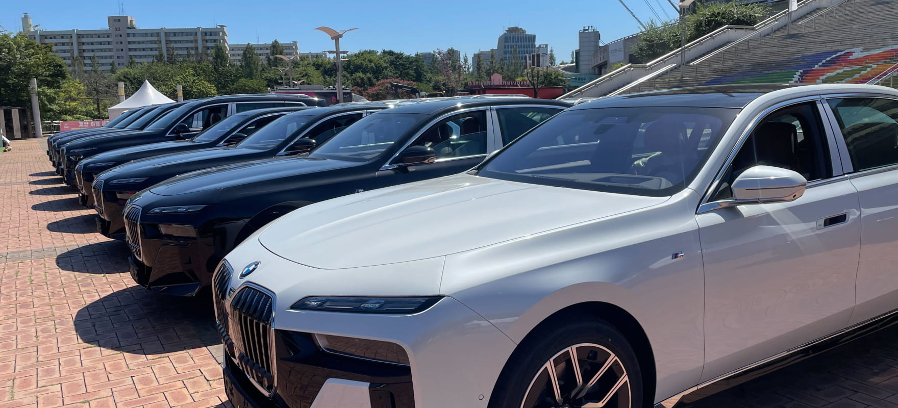 A lineup of premium BMW 7 Series sedans prepared for VIP protocol services at the ICONS Match outdoor staging area.