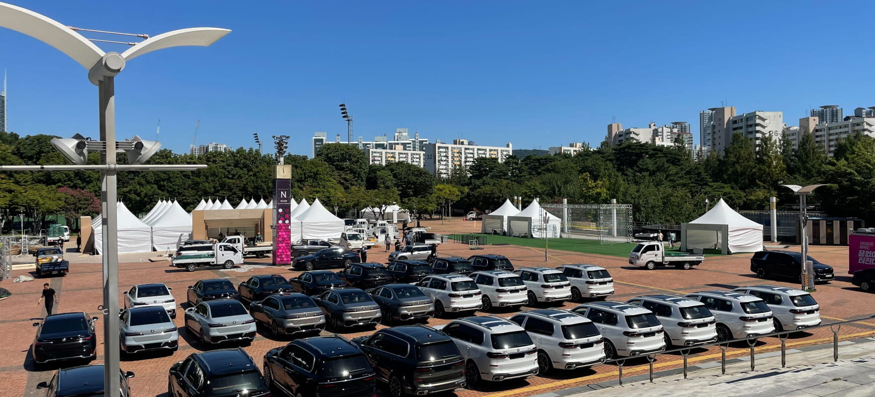 Wide view of the outdoor mobility staging area featuring rows of BMW SUVs and sedans for the 2025 ICONS Match operations.