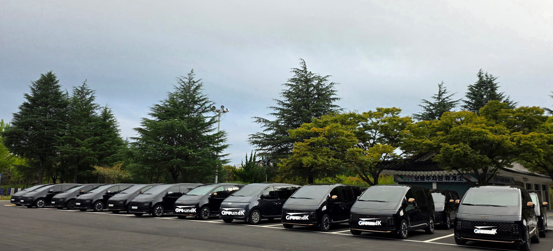 A row of black Hyundai Staria vans with GroundK logos parked outdoors for APEC 2025 Korea transportation services.
